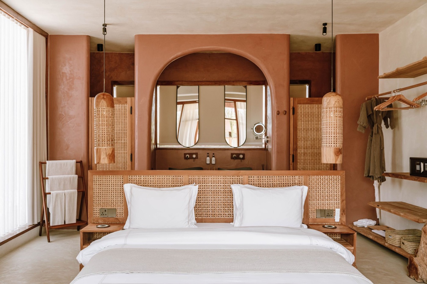 Bedroom with arched mirrors above a bed dressed in white linen